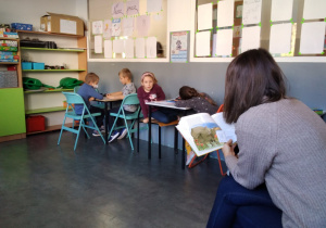 Na zdjęciu nauczyciel biblioteki trzymający książkę, czyta dzieciom opowiadania o Detektywie Pozytywce.